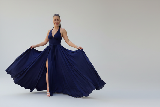 Woman in a navy blue dress with a high slit standing
