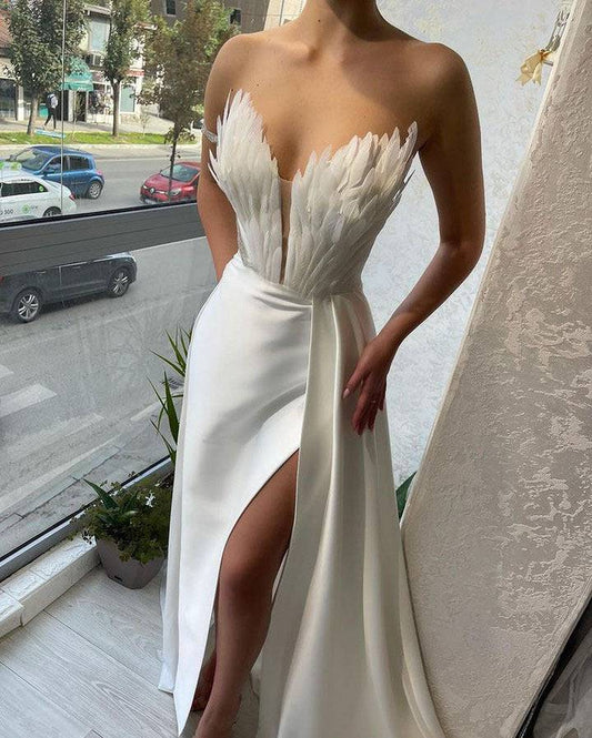 White strapless gown with a high slit on a person standing on a balcony.