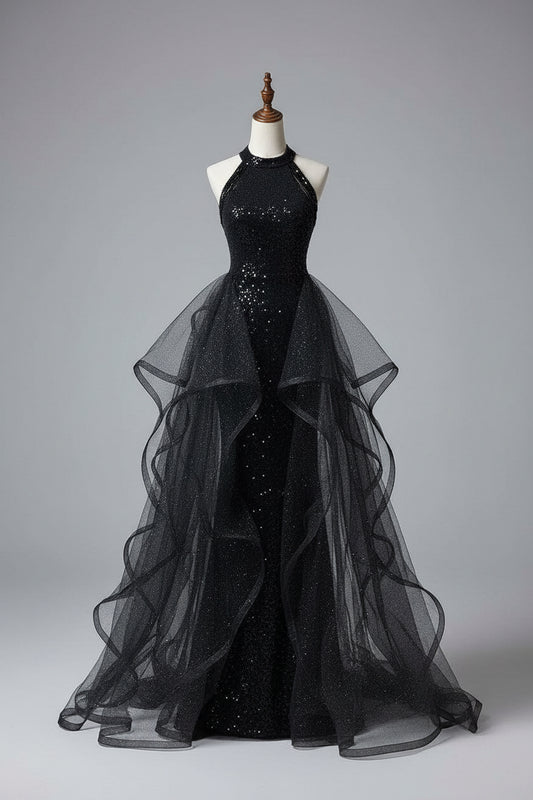 Black evening gown with sheer overlay on a mannequin against a neutral wall.